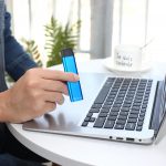 Person holding blue vape Kiwipod N1 while working in Laptop